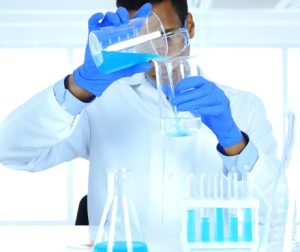 Lab technician mixing liquids in glass containers