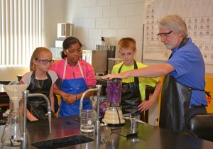 Science Camp participants, from left, Tara Journigan of Henderson, Janea Camacho of Oxford and Ethan Hann of Oxford, with VGCC Science Department Chair Steve McGrady, conduct an experiment using red cabbage during a session on chemistry.