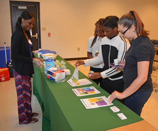 N.C. Cooperative Extension Agent Dominque Simon provides fresh vegetables and information on health and nutrition to VGCC/Warren Early College High School students Nubia Lockett, Kiah Durham and Raina Mills during the Earth Day celebration.