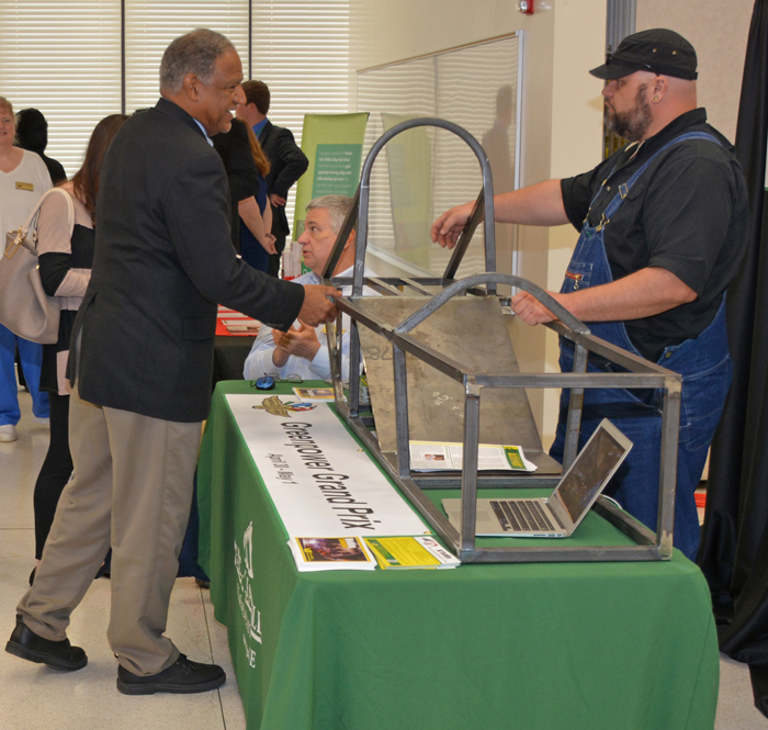 Wilson Community College trustee Kenneth Jones (left) checks out VGCC’s display at the press conference, featuring the frame of a car that, when complete, will race in a national competition. Standing at right is VGCC Welding student Josh Pfohl, who took the lead on building the frame, which will be finished by a combination of Welding and Mechatronics Engineering students.