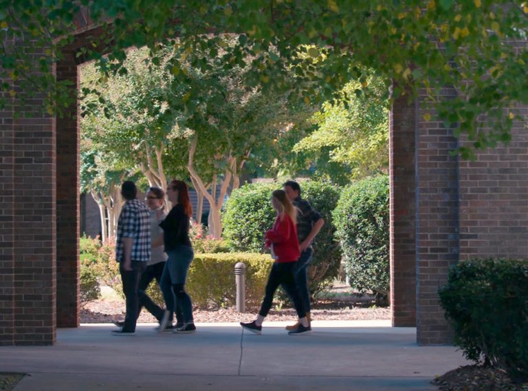 students walking through main campus courtyard arches