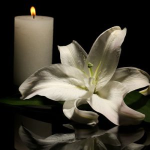 Photo of a burning candle and a flower