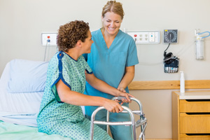 Nurse aide assisting a patient with getting out of the bed.