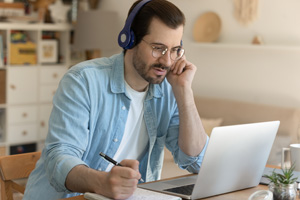 Student wearing headphones looking at his laptop.
