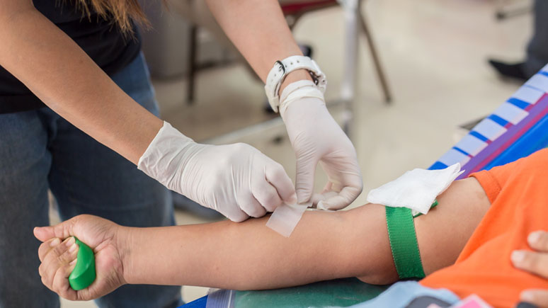 Phlebotomist preparing a patient's arm for drawing blood.