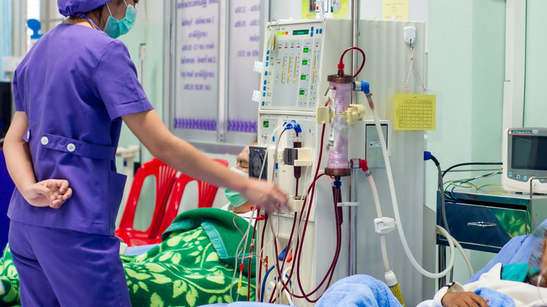 Dialysis tech maintaining dialysis equipment at the bedside of a patient. 