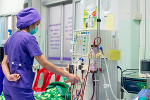 Dialysis tech maintaining dialysis equipment at the bedside of a patient.