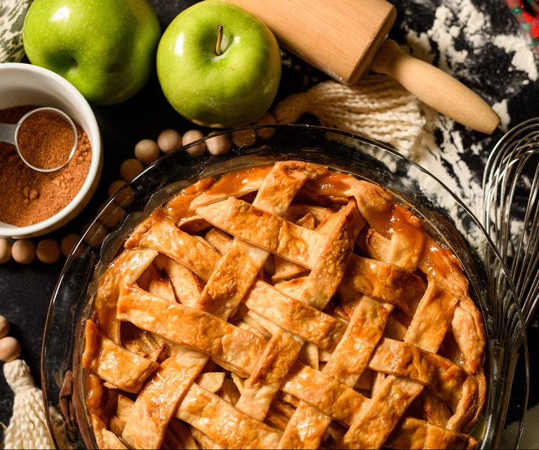 Apple pie with lattice design surrounded by ingredients and baking tools [Shutterstock 2088944338]