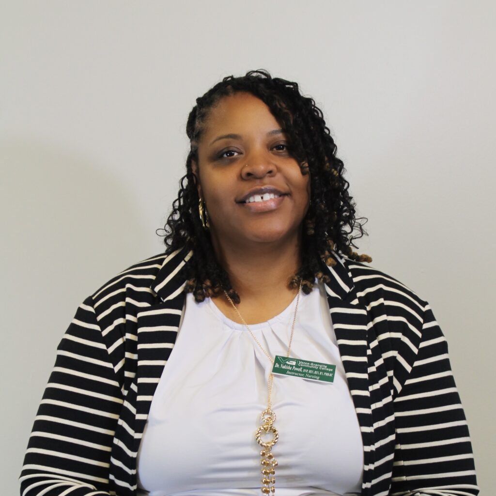 Dr. Nakisha Powell smiling in front of an all white background.