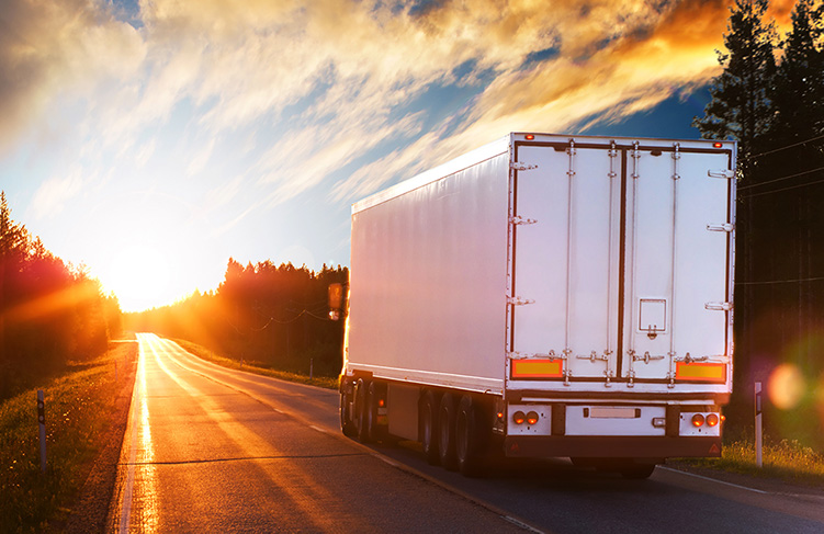 Large box truck driving into the sunset