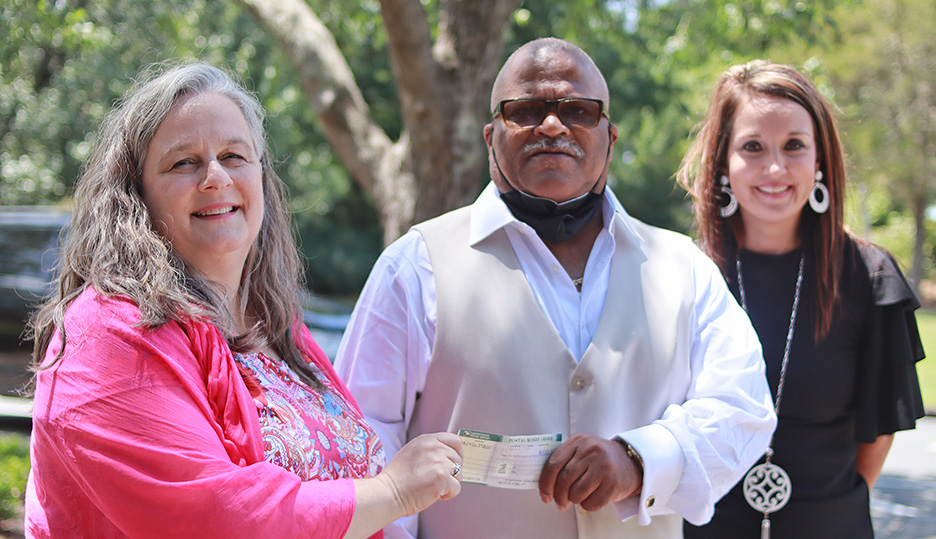 A man presents two women with a check