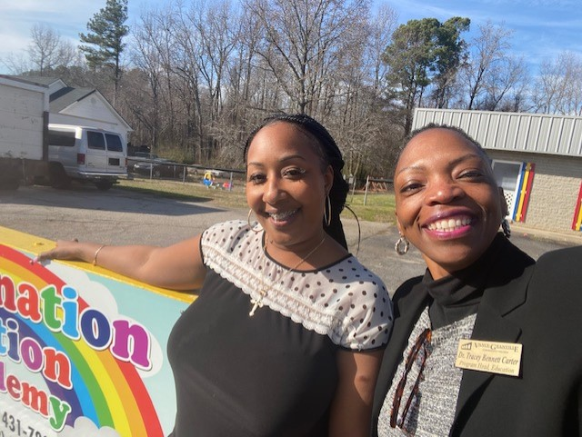 Two women take a selfie beside a daycare sign