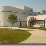 South Campus walkway; a sidewalk leading up to a white building with two trees on either side.
