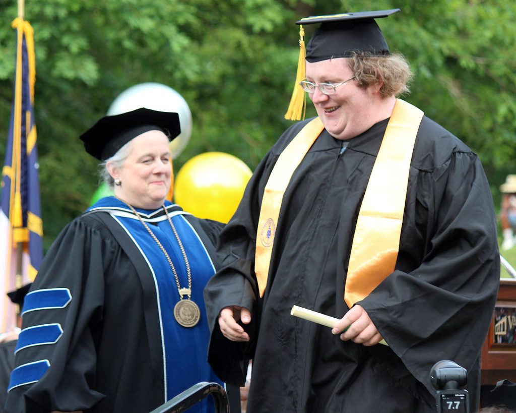 VGCC President Dr. Rachel Desmarais (left) looks on as a graduate crosses the stage during the College's 2023 commencement exercises.