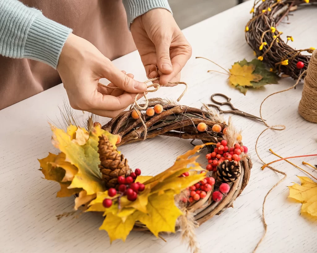 Florist making beautiful autumn wreath at table [Shutterstock ID 2054261660]
