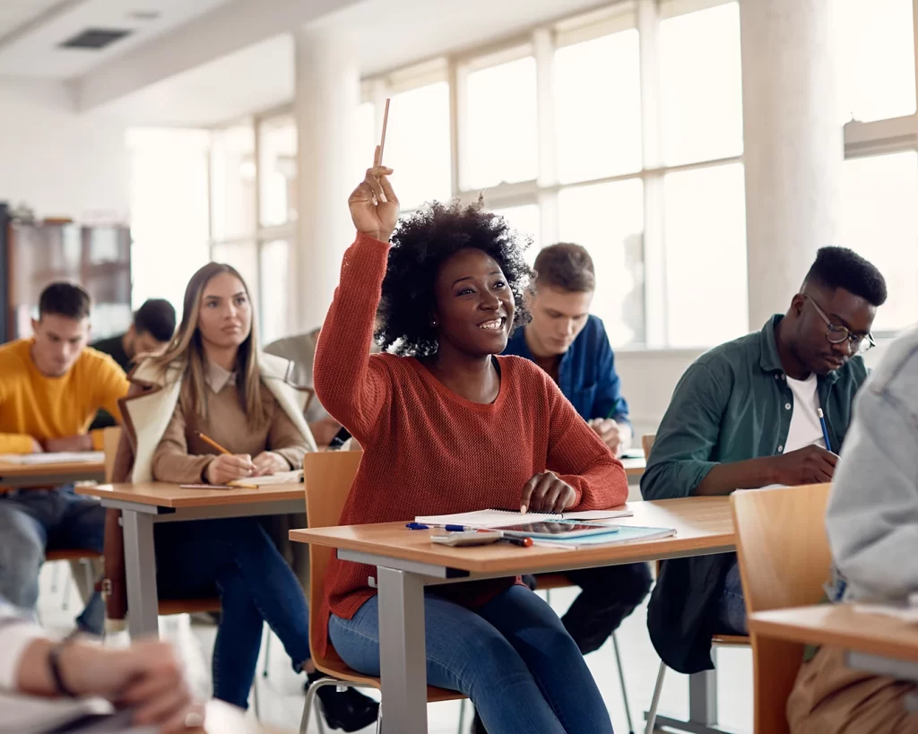 Happy African American student raising her hand to ask a question during a lecture.