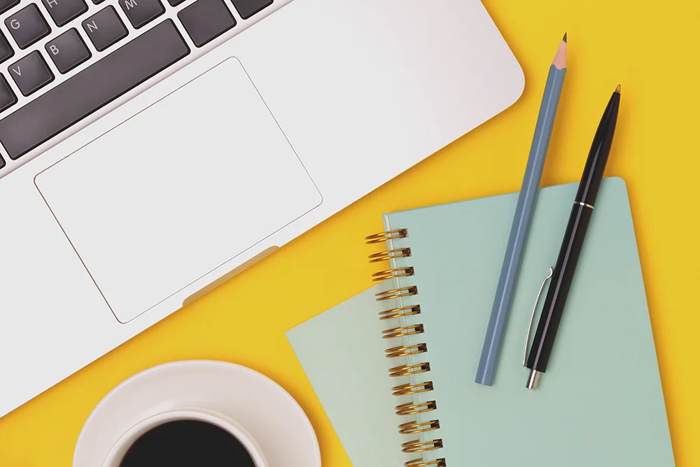 A laptop next to a small notebook with a pen and pencil. Used to represent other types of testing at VGCC.
