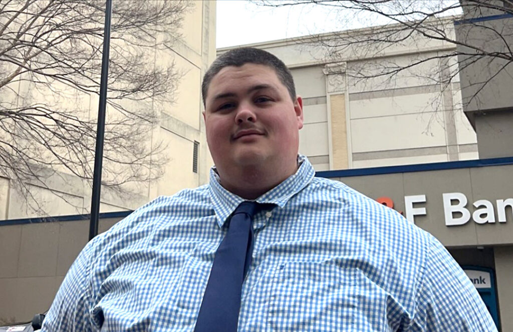 Closeup photo of a young man in professional clothing, taken outdoors in an urban setting
