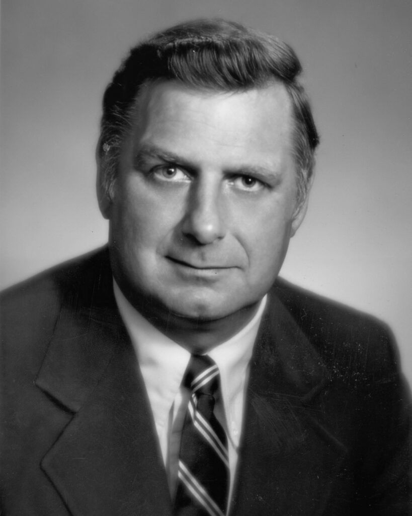 Formal grayscale photo portrait of a mature white man in a business suit (undated)