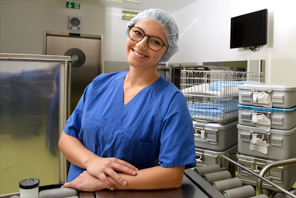 A young woman dressed in special medical hygiene clothing stands surrounded by hospital equipment [Shutterstock photo #1305041872]