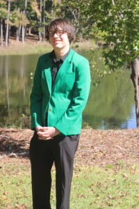 George Grissom wearing a green VGCC ambassador's coat outside in front of the main campus pond.