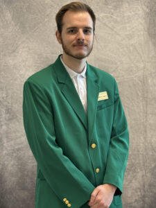 Matthew James wearing a green VGCC Ambassadors coat.