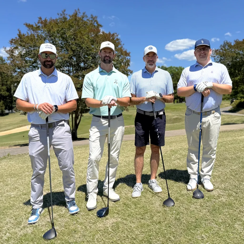 A four-person golf team poses with drivers on the Henderson Country Club golf course.