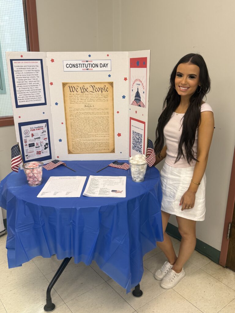 McKenzie Munafo standing with a tri-board Constitution Day presentation.