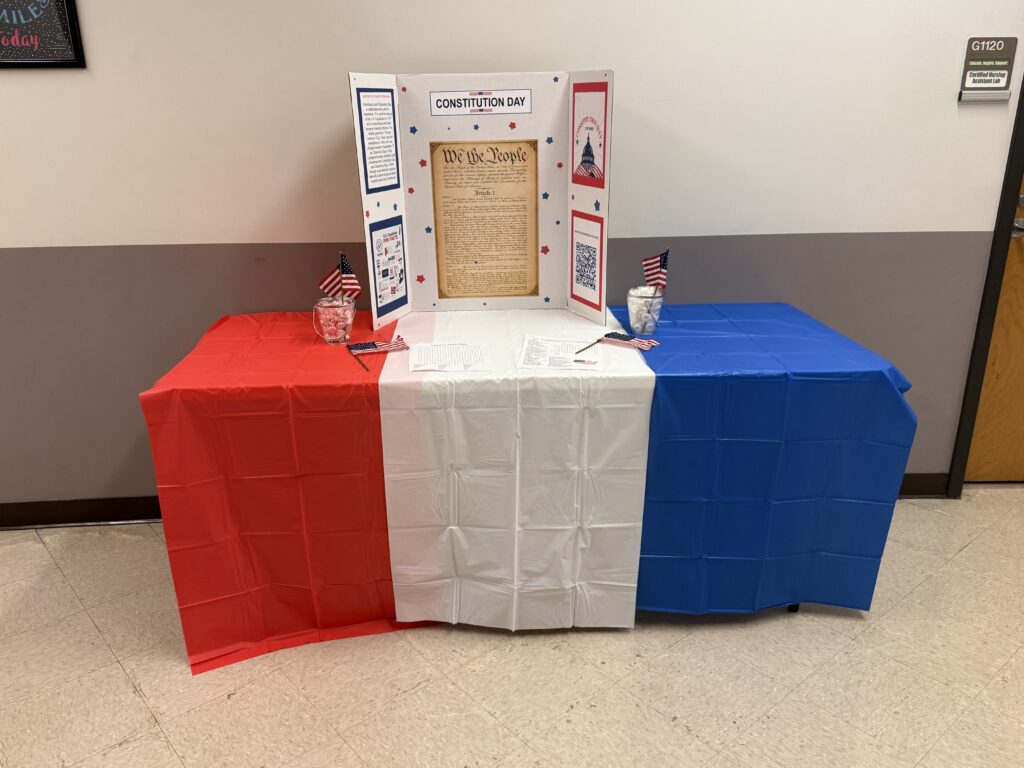 A constitution day tri-fold presentation on a table with red, white, and blue table cloths.